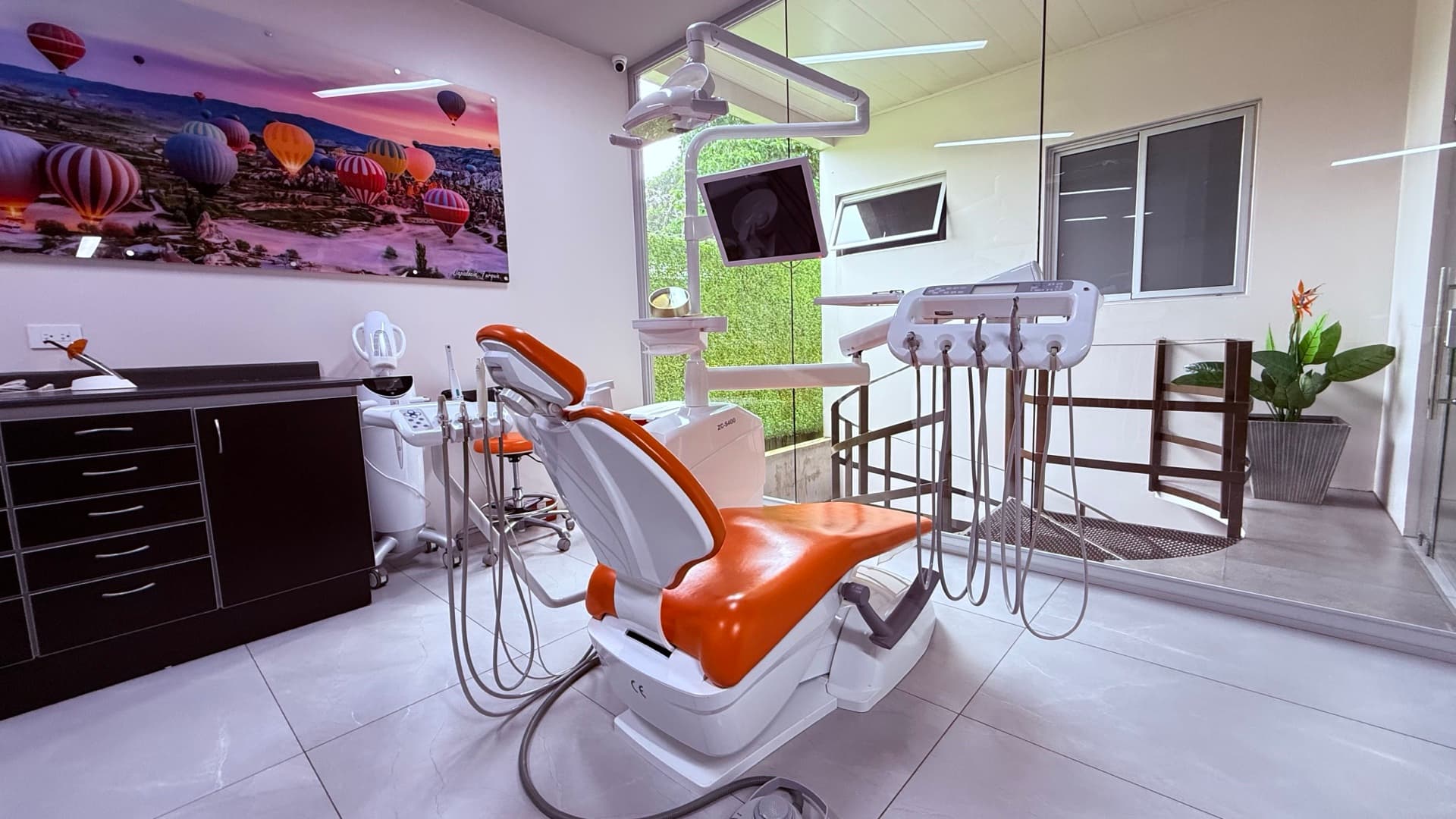 Treatment room with orange dental chair and Cappadocia wall art