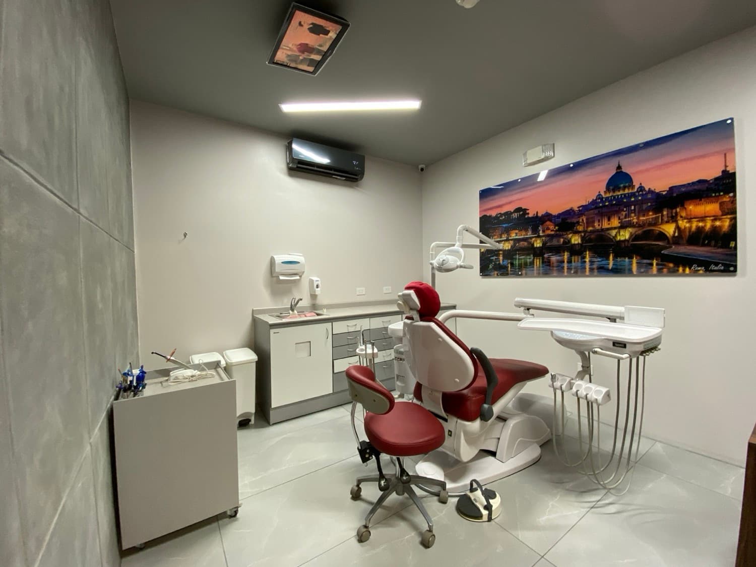 Treatment room with red dental chair and Roma, Italia wall art