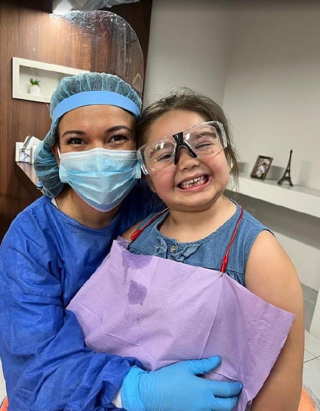 Smiling little girl with safety goggles and dental assistant
