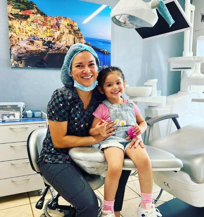 Dental assistant with happy little girl in the treatment room